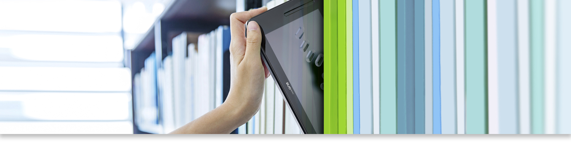 The picture shows a hand picking up the insideONE Braille tactile tablet stored in a bookcase like a book.
